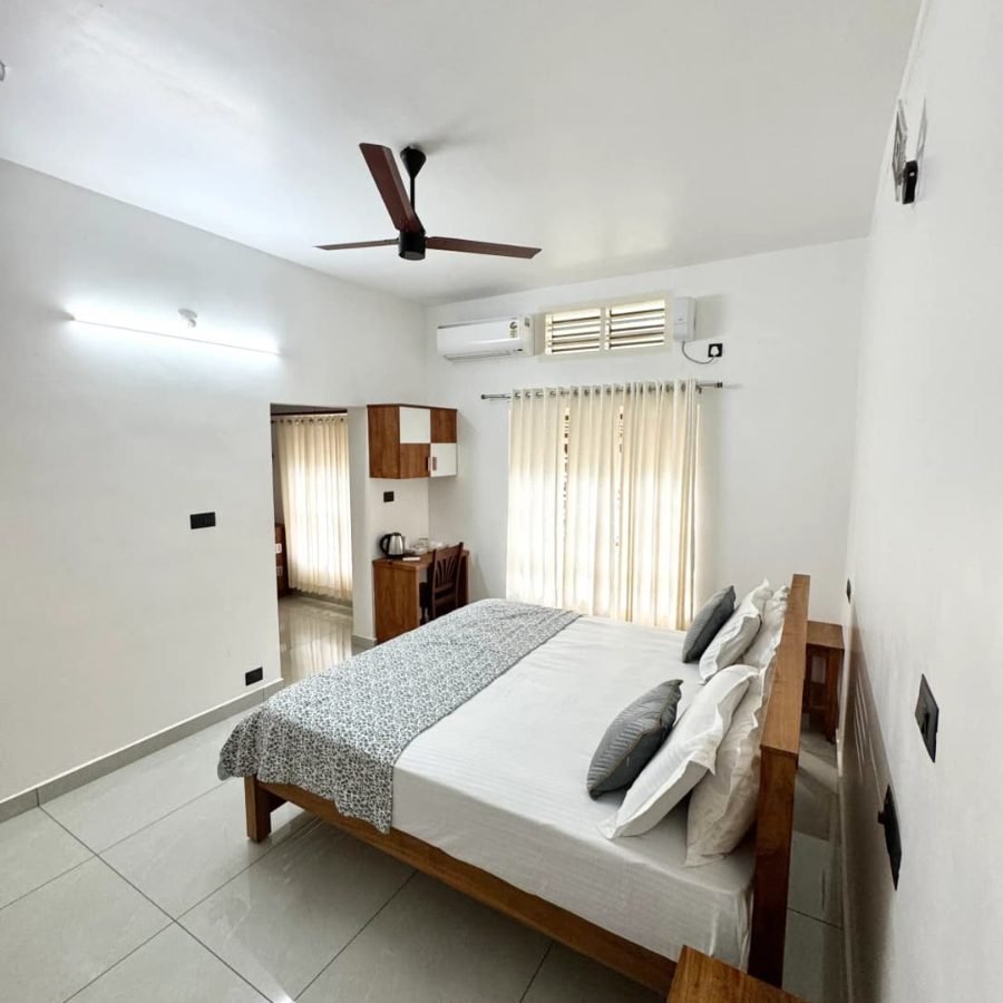 Spacious air-conditioned bedroom at Jeevika Haven with large wooden bed